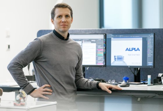 ALPLA employee Daniel Lehner on his desk in front of 2 screens