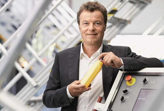 ALPLA CEO Guenther Lehner is holding a yellow button in is hands. 